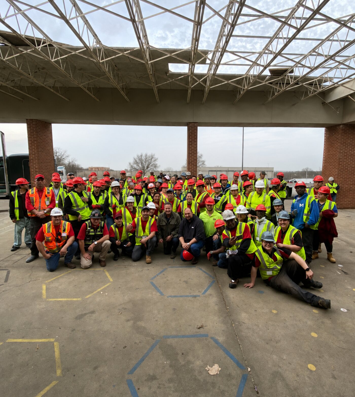 Large group of Workforce Pros construction workers in hard hats and safety vests posing together on a job site